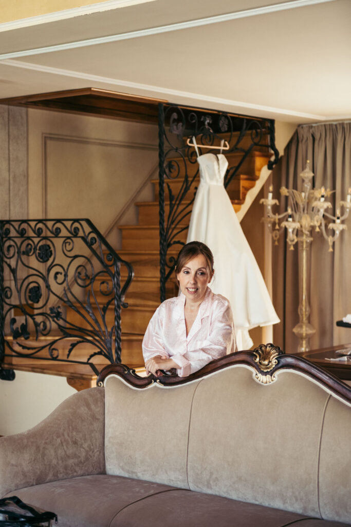 The mother of the bride smiles radiantly as she assists in the bridal preparations, adding a touch of joy and love to the intimate scene