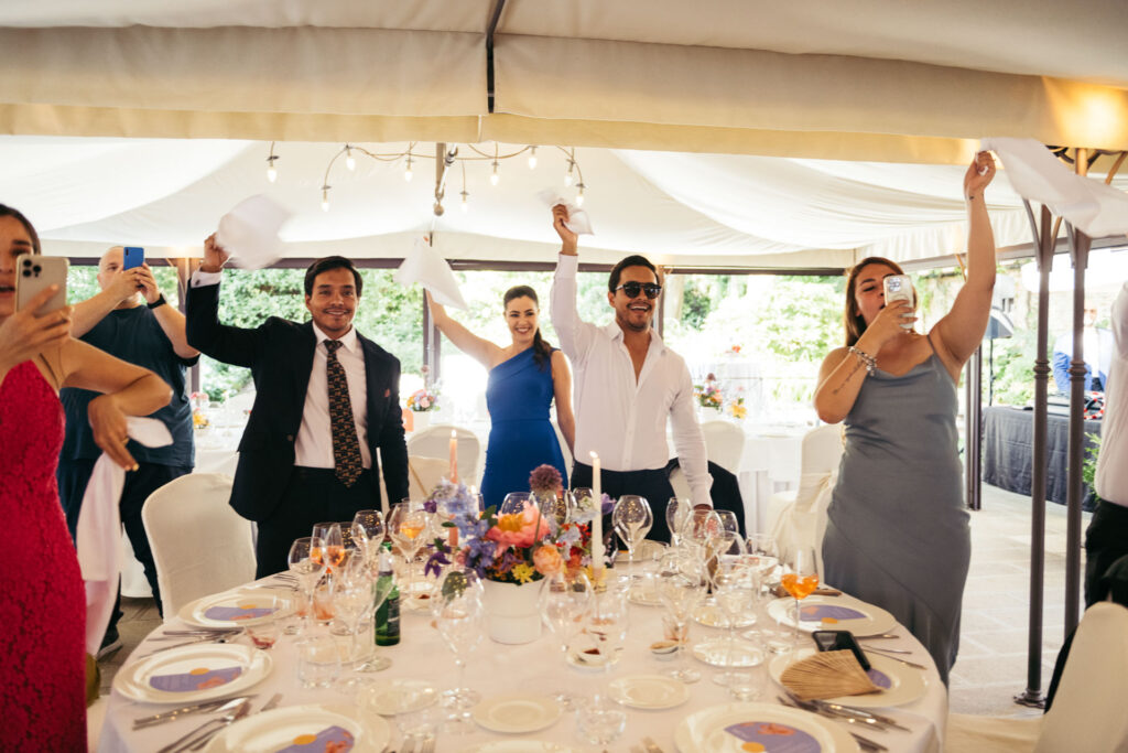 Guests celebrate with joy, raising their glasses in a spirited toast to the newlyweds, creating a festive and memorable atmosphere