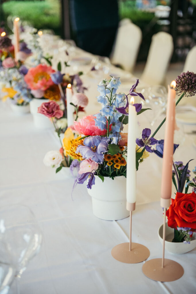 The wedding reception features exquisite tableware and colorful flowers, creating a sophisticated and inviting ambiance for guests to celebrate the newlyweds' union in Venice Italy