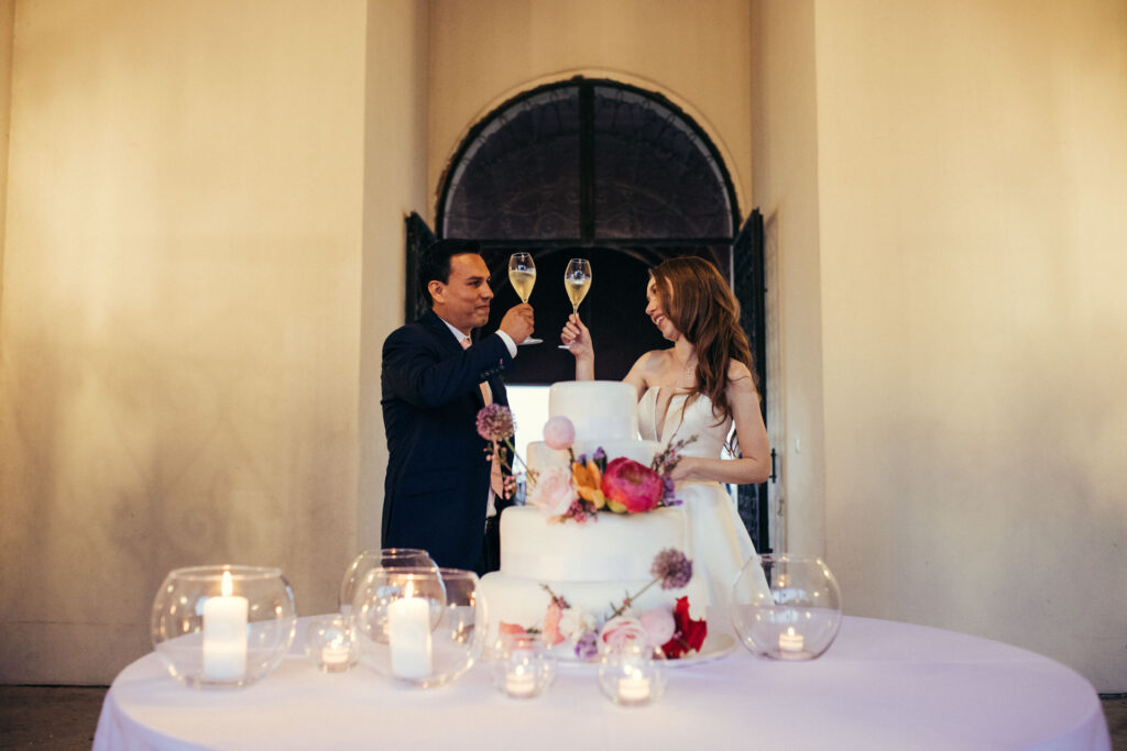 The bride and groom raise their glasses in a joyous toast, marking a moment of shared happiness and celebration on their special day