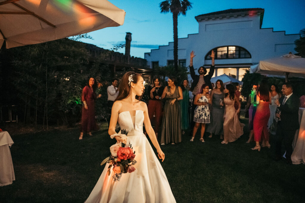 The bride joyfully throws the bouquet, creating an anticipation-filled moment as eager guests reach for the chance to catch this cherished symbol of luck and love