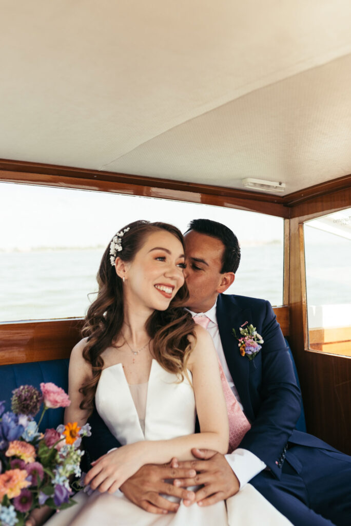 Enchanting portrait of the bride and groom on a water taxi, framed by the picturesque canals of Venice, capturing the romance of their journey to the wedding ceremony