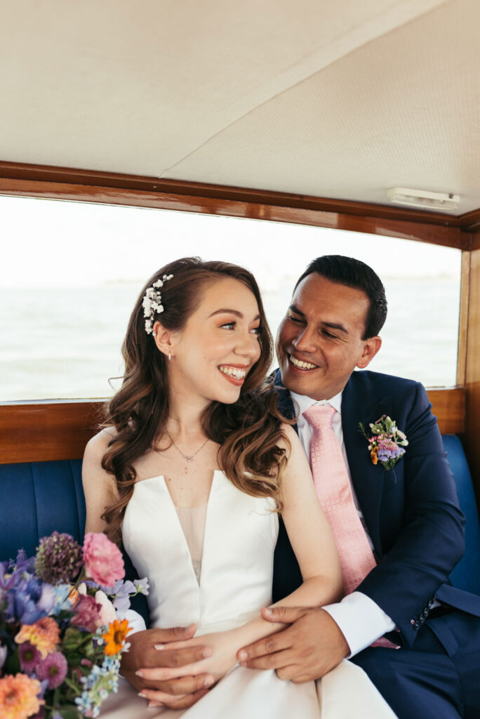 Enchanting portrait of the bride and groom on a water taxi, framed by the picturesque canals of Venice, capturing the romance of their journey to the wedding ceremony