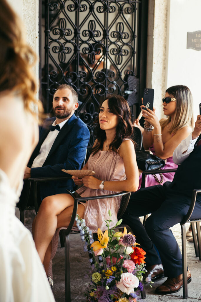 Guests share in the joyous atmosphere of the wedding ceremony at the NH Collection Venezia Grand Hotel Palazzo dei Dogi, creating cherished moments of celebration