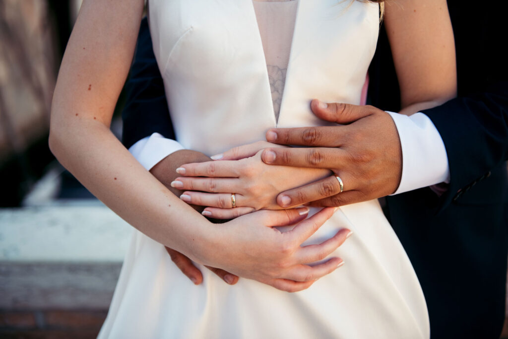 A close-up of hands adorned with wedding bands, capturing the intricate beauty of the symbolic union in this timeless portrait