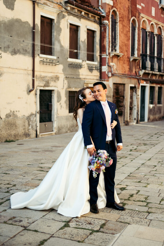 The bride and groom strike a pose on their wedding day, framed by the timeless beauty of Venice, creating a stunning and memorable portrait