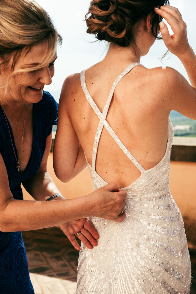 Close-up of mum of the bride helping her with the dress