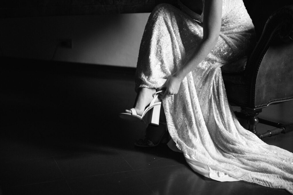 Black and white detail of the bride putting on her shoes