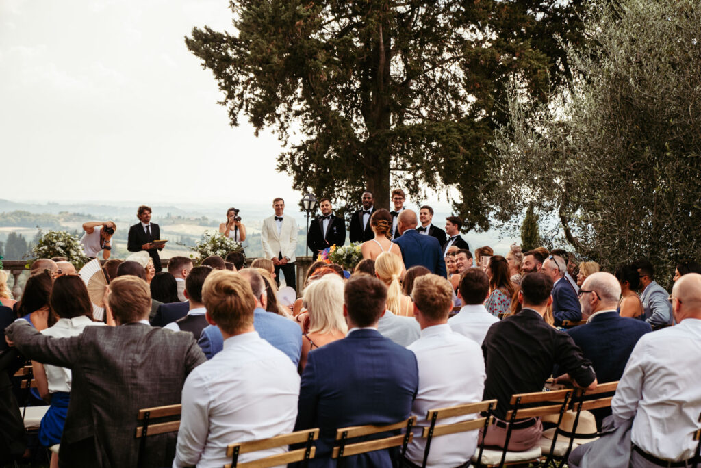 Bride walks down the aisle as the groom looks at her smiling