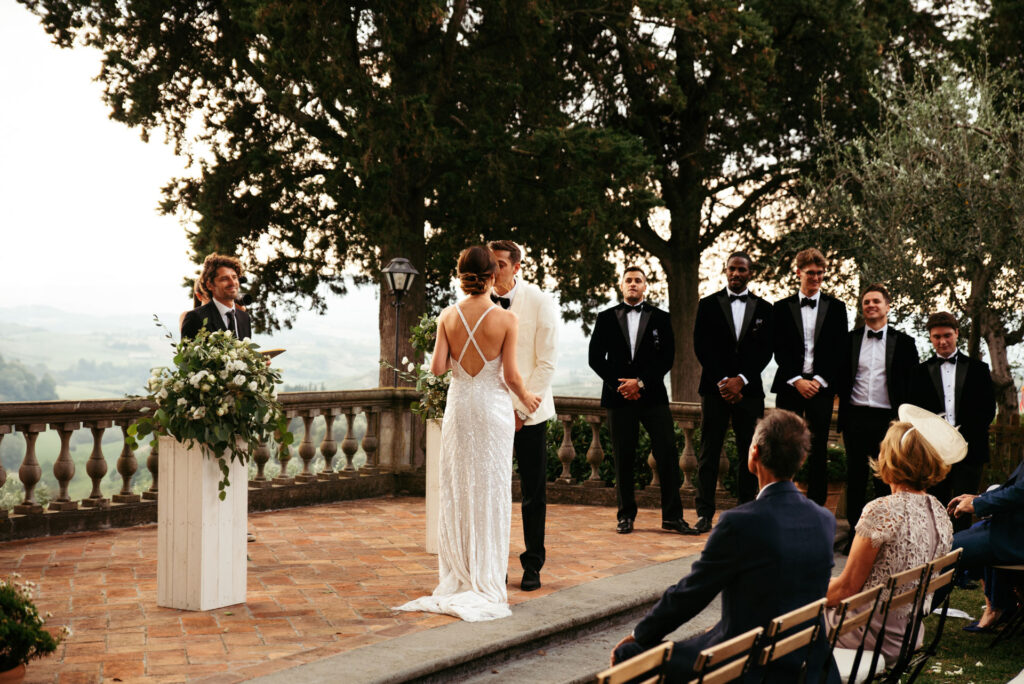 Bride and groom are together with best mans on the background