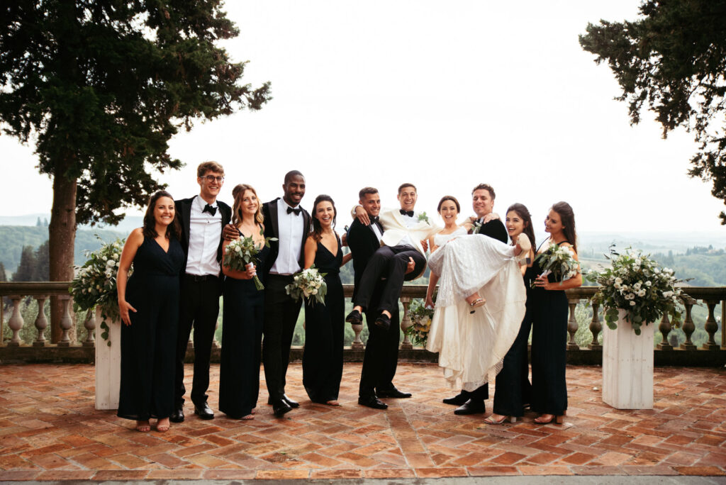 Bridesmaid and groomsman lifting bride and groom while posing for a photo