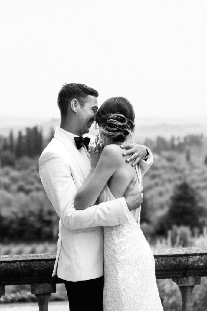 B&W photo of newlyweds hugging against the picturesque backdrop of the Tuscan countryside, celebrating their marriage in Italy