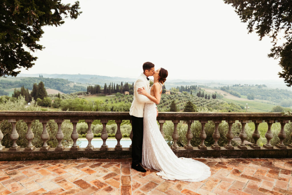 Newlyweds share a kiss against the picturesque backdrop of the Tuscan countryside, celebrating their marriage in Italy