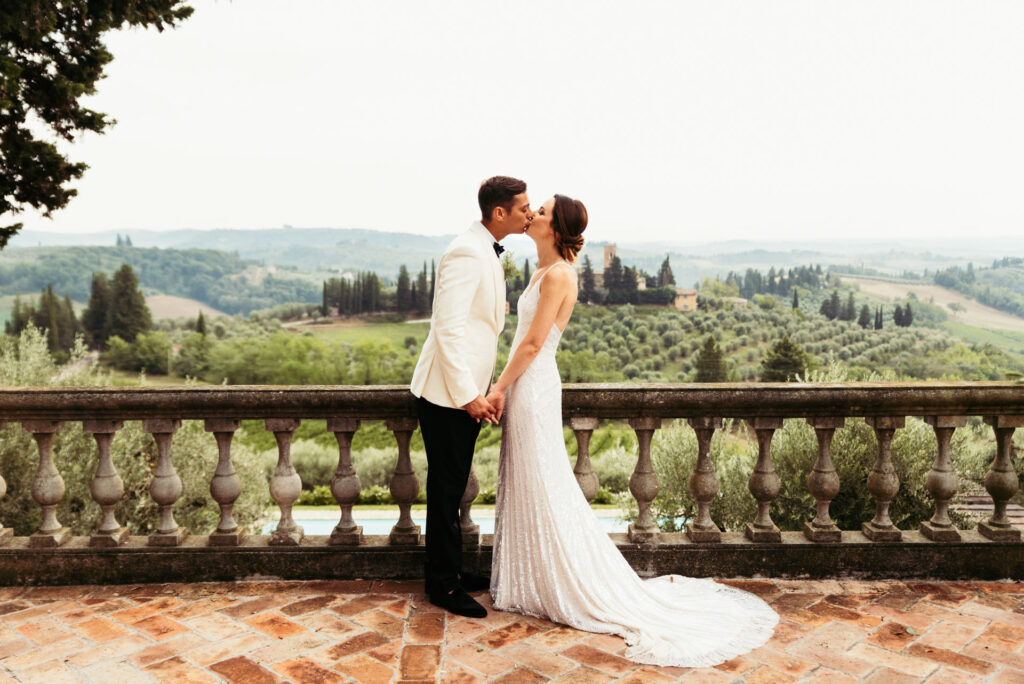 Newlyweds share a kiss against the picturesque backdrop of the Tuscan countryside, celebrating their marriage in Italy