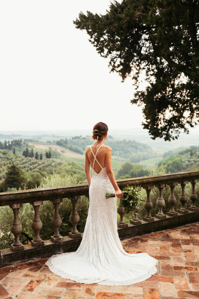 Photo of the back of the bride while she's looking to Tuscany landscape