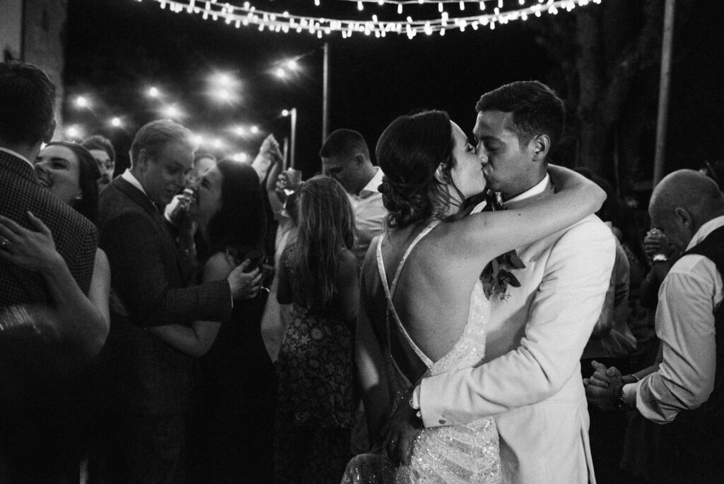 Bride and groom share a kiss on the dance floor under the lights