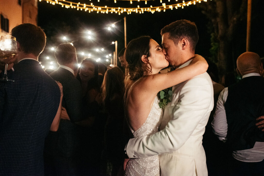 Bride and groom share a kiss on the dance floor under the lights