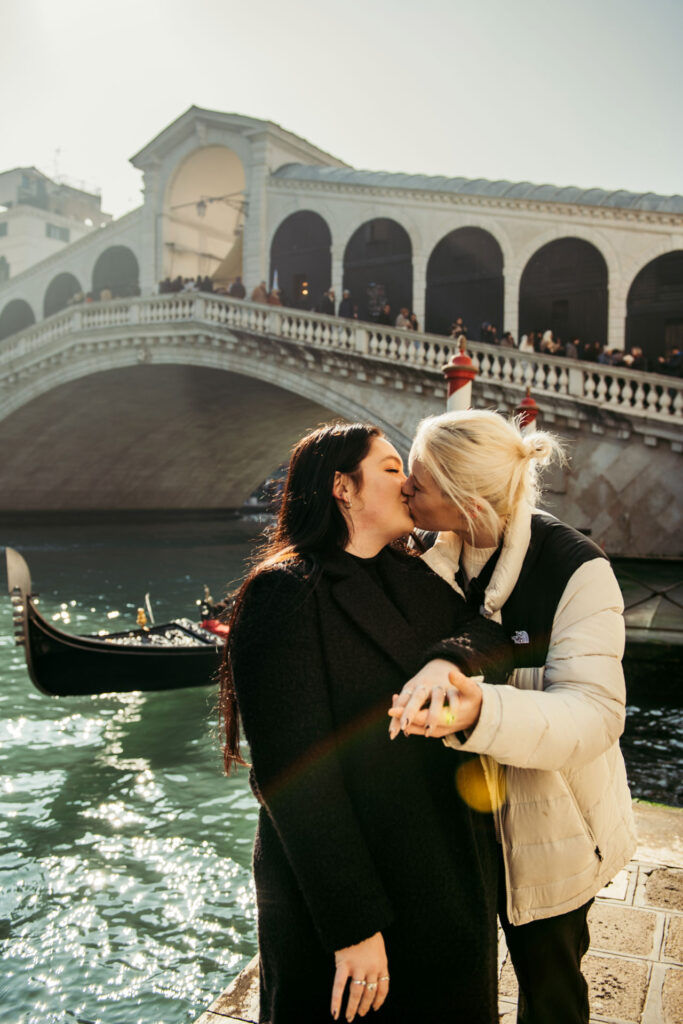 A same sex couple kiss under the Rialto bridge after they just got engaged