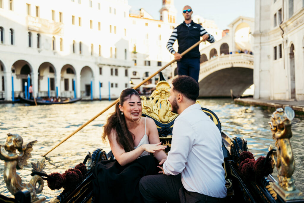 Girl crying with joy as he puts the engagement ring on her finger on a gondola in Venice