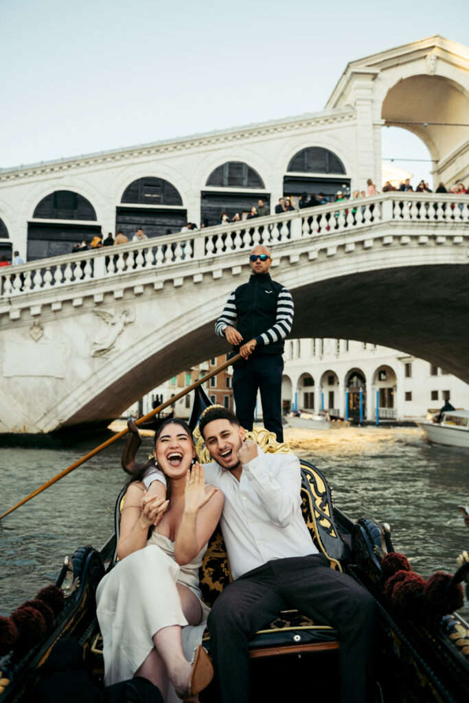 Happy couple newly engaged, smiling while enjoying a romantic gondola ride in Venice during a photoshoot