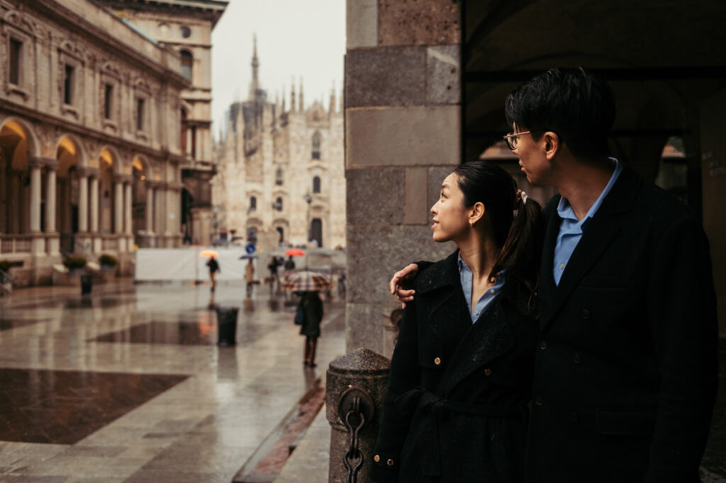 Couple looking at the rain with Duomo di Milano on the background
