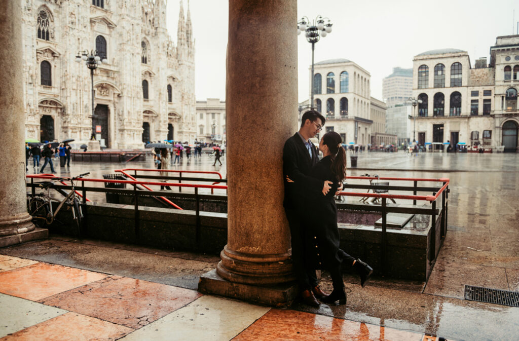 Couple hugging against a coloumn in Piazza Duomo Milan