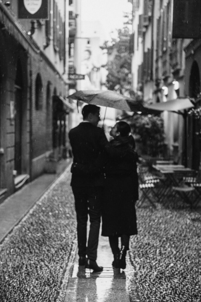 Couple walking in the Brera quarter during heavy rain