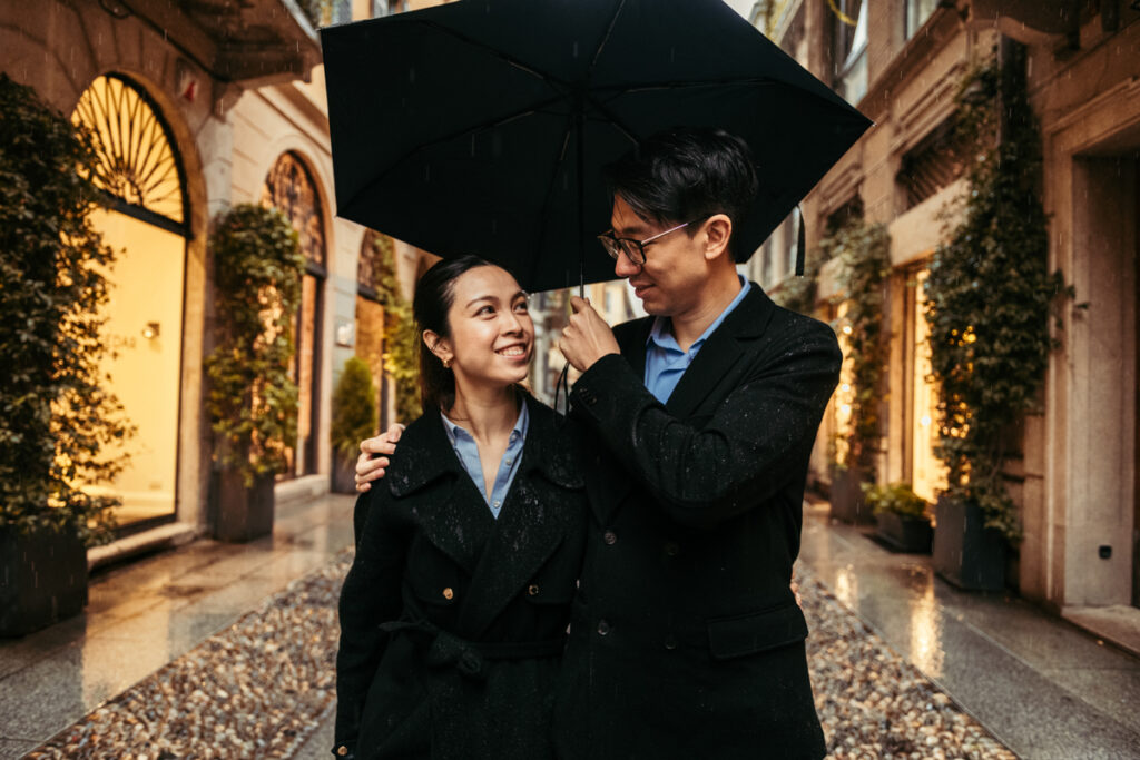 A man hugs his girlfriend while holding an umbrella in Brera, Milan