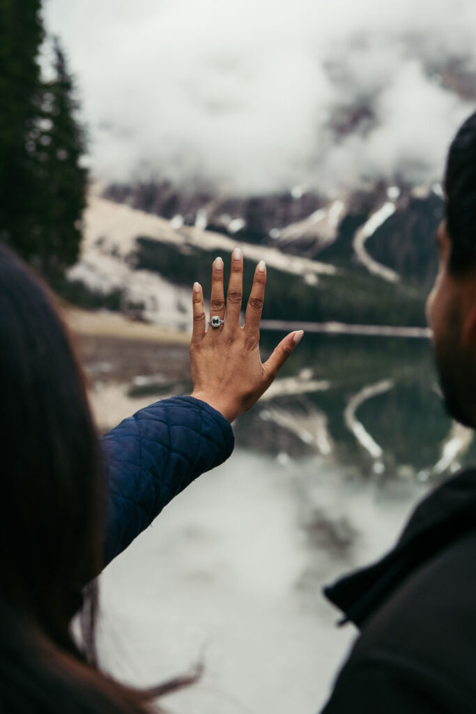 Couple looking at the engagement ring with Lake Braies on the background