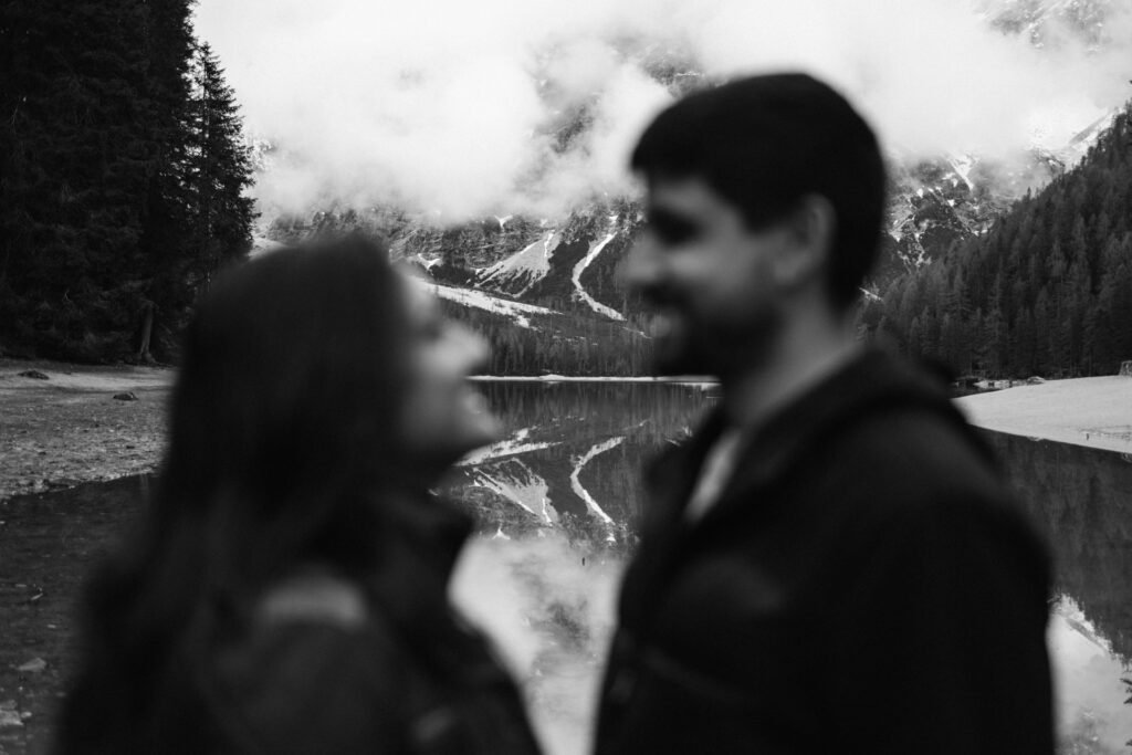 B&W photo of couple blurred with Lake Braies on focus in the background