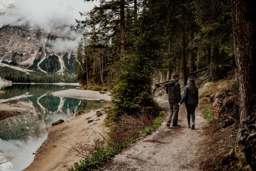 Couple walking down the path that surrounds Lake Braies at Dolomites, Italy