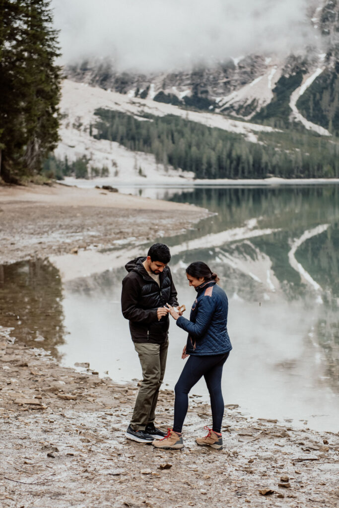 Man putting a ring on his girlfriend's hand at Lake Braies in Dolomites, Italy