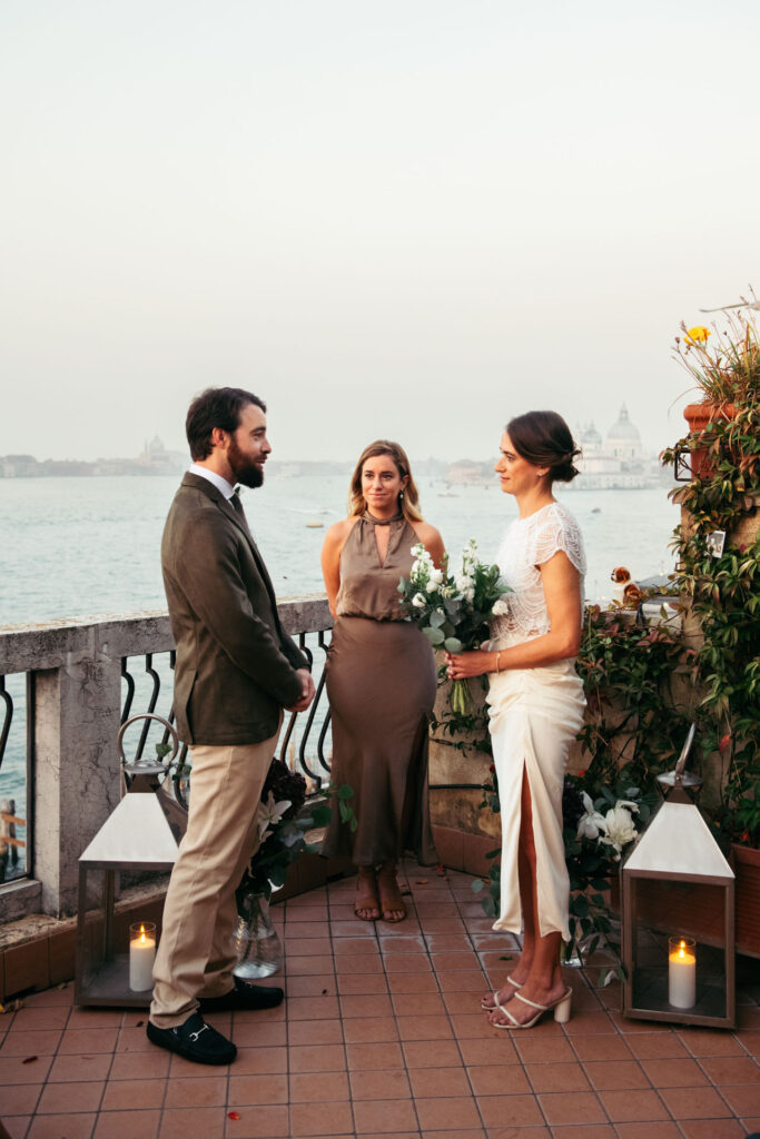 Groom and bride exchanging vows in front of the officiant during sunrise