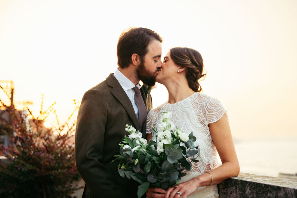 Bride and groom's kiss with sunrise sunshine behind them