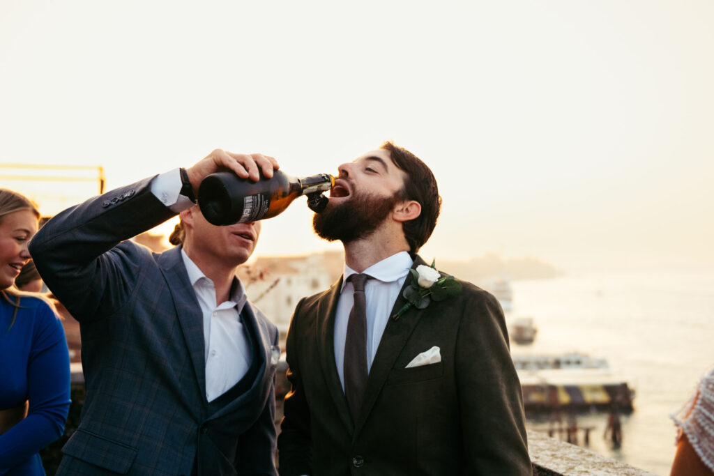 The groom drinks directly from the bottle to celebrate