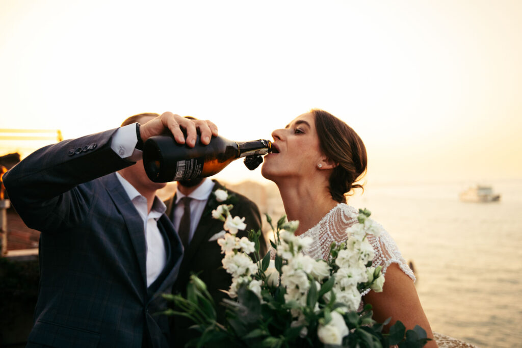 The bride drinks from the bottle to celebrate