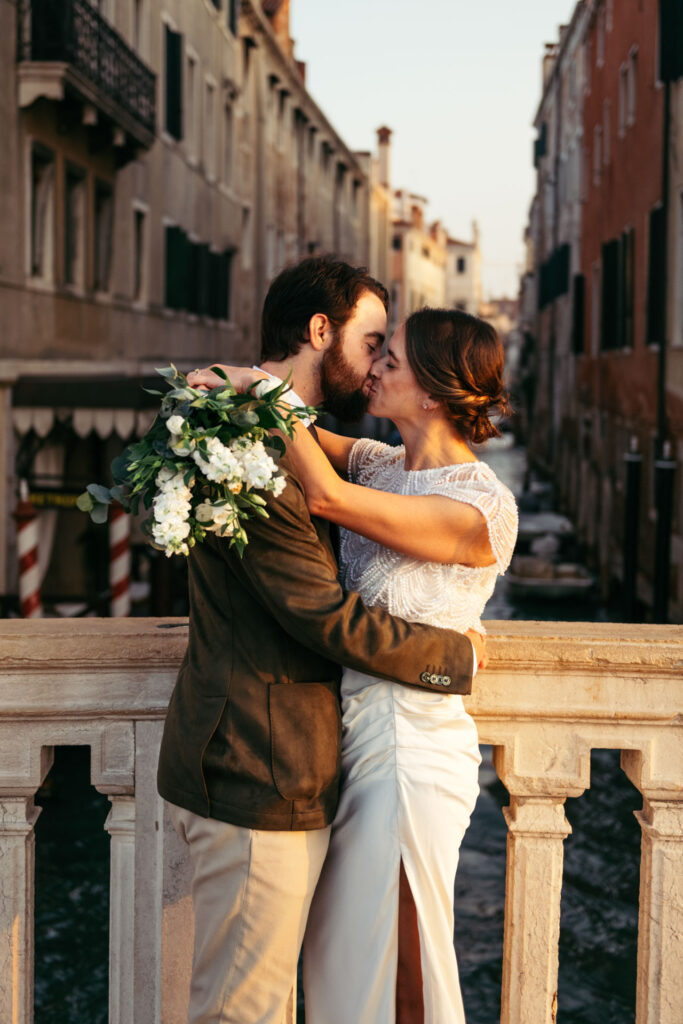 Bride and groom kiss on a bridge in Venice