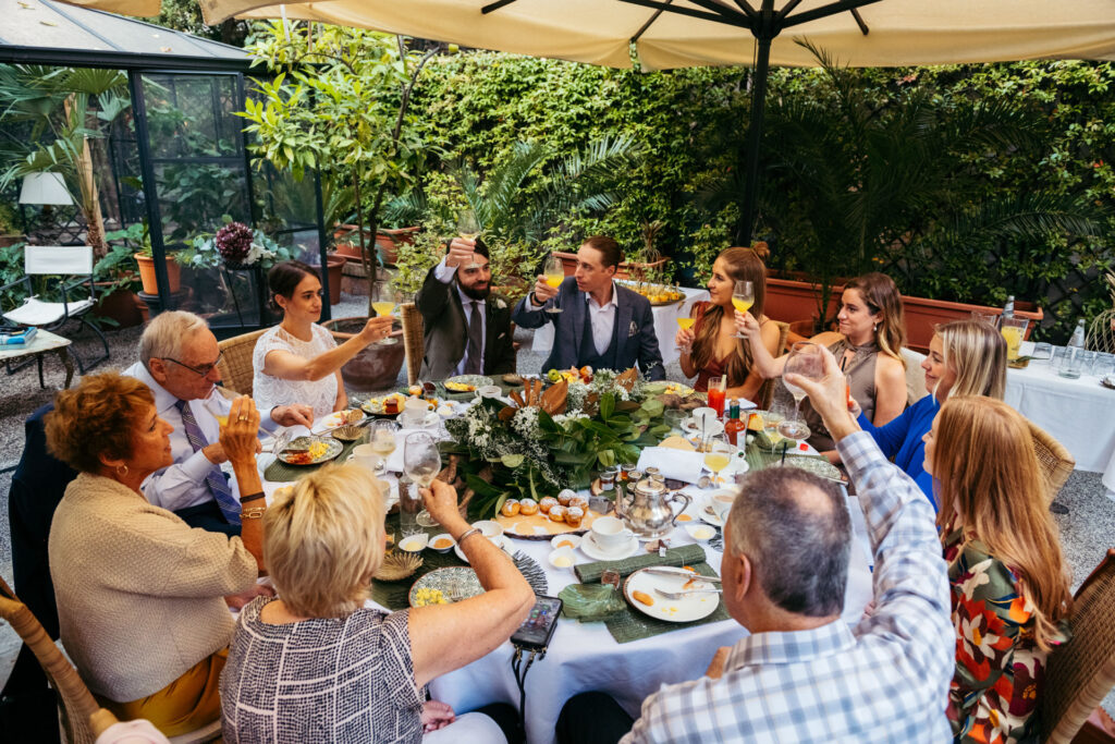 Guests, bride and groom are making a toast around their breakfast table