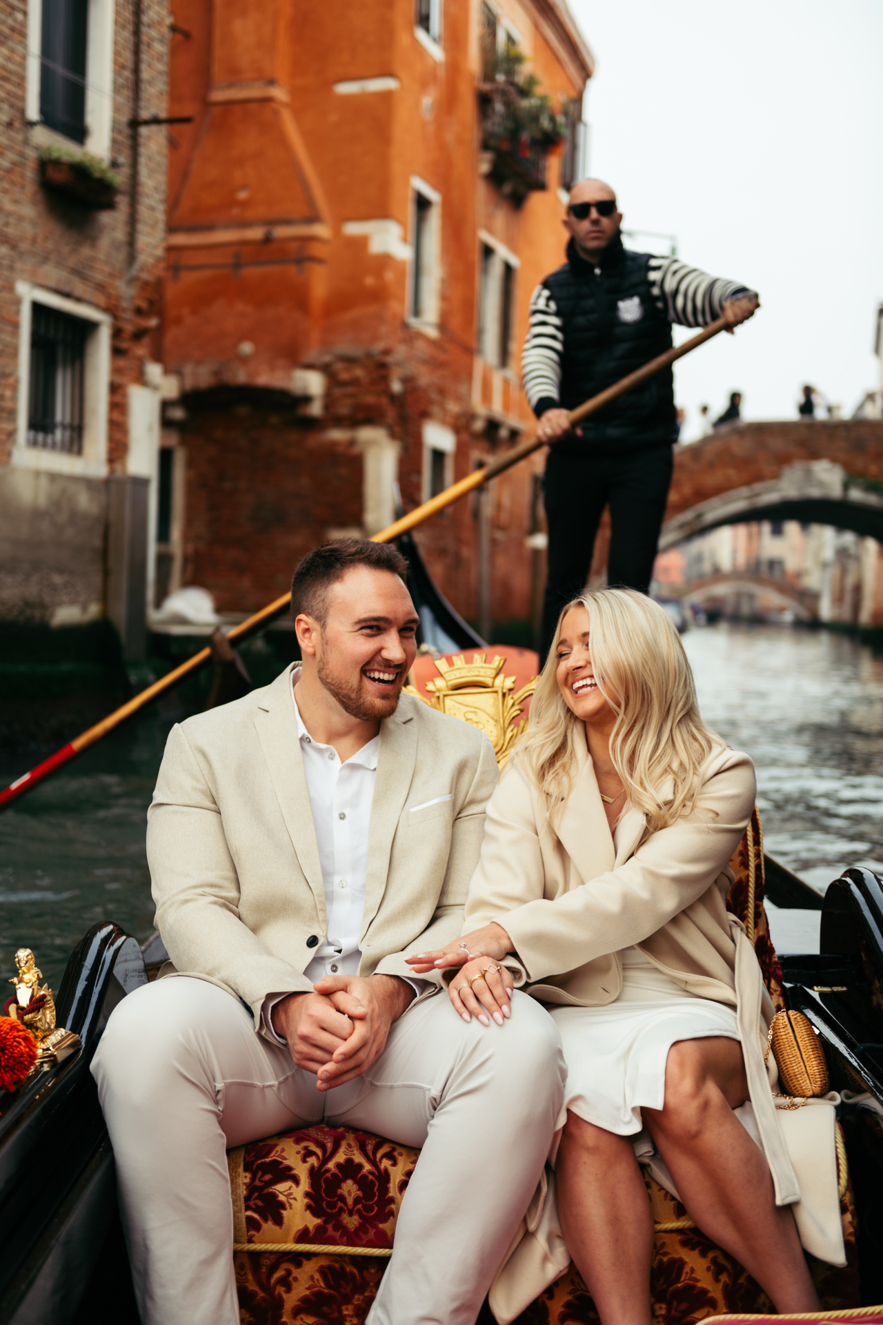 A couple laughing and smiling on a gondola in Venice, Italy after getting engaged