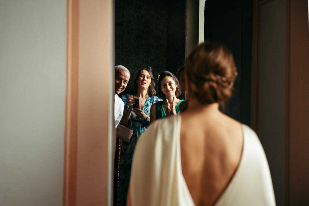 Bridesmaids and bride's dad cheering when they see her dressed up for the first time