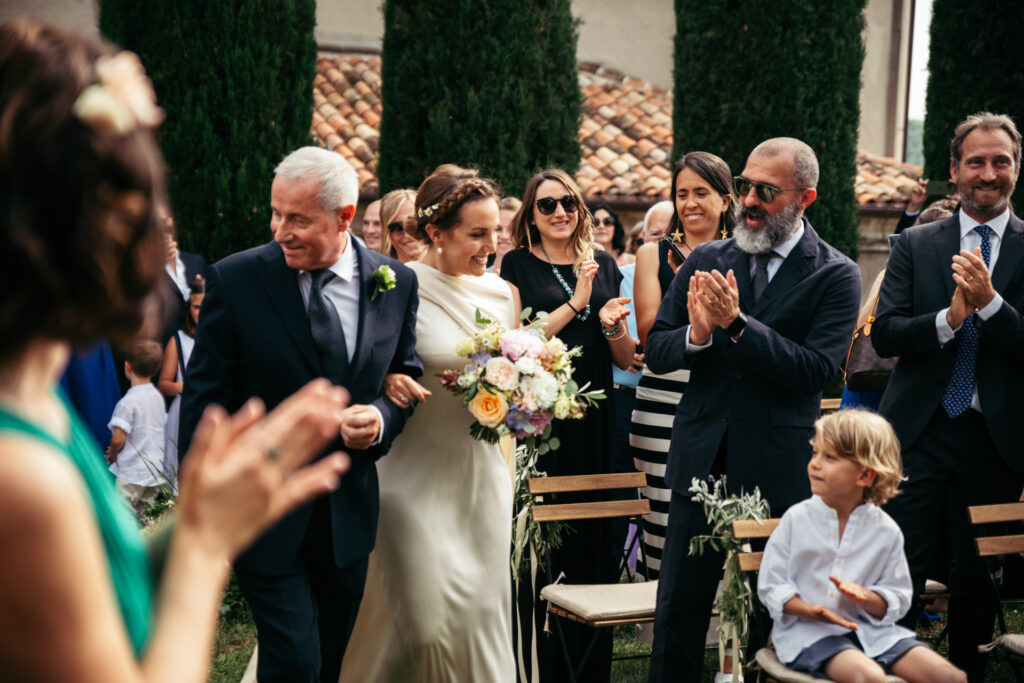 Bride and her dad walking down the aisle while guests applaude