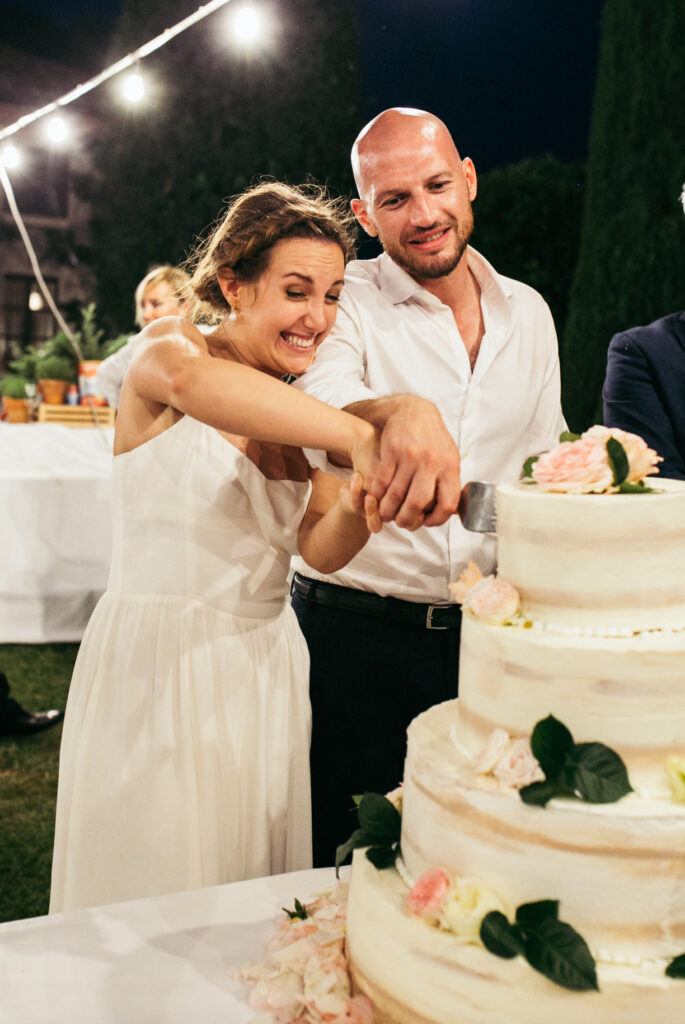 Bride and groom cut the cake at night during wedding in Langhe Piedmont