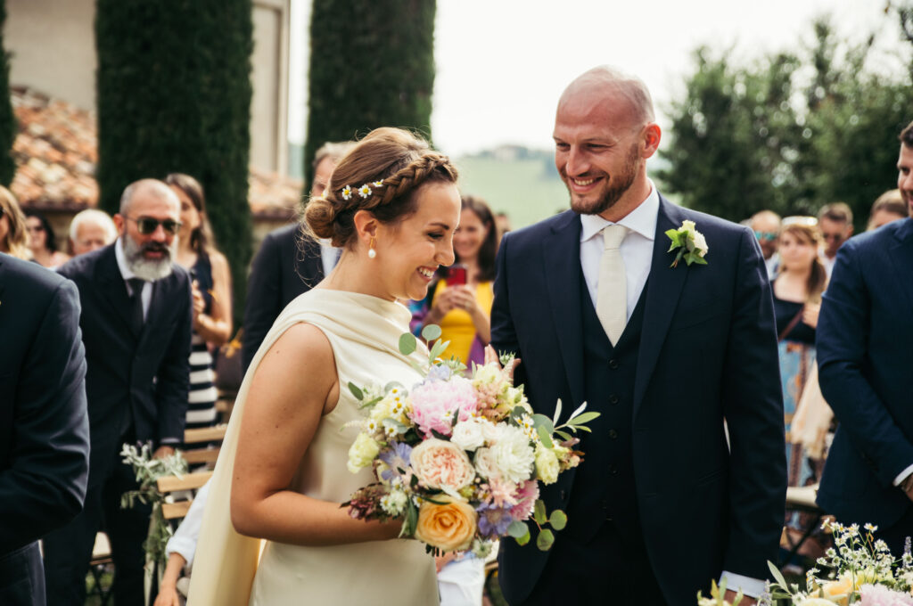 Bride and groom smiles happily during the outdoor ceremony at Castello di Coazzolo