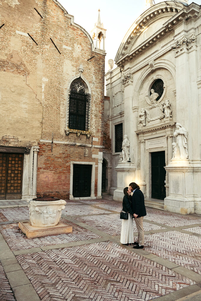 Long shot of a couple kissing in the middle of a small square in Venice Italy