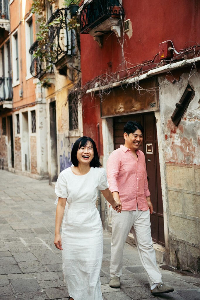 Couple laughing while walking down a colorful alley in Venice