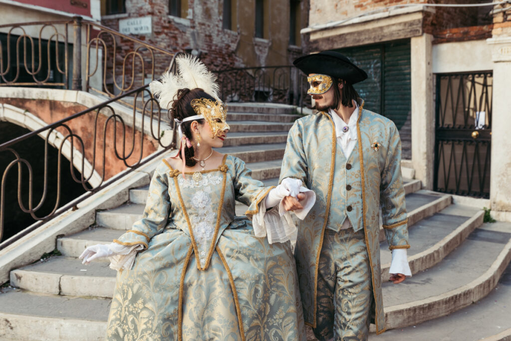 Couple dressed in 18th-century Venetian costumes strolling through the historic streets of Venice