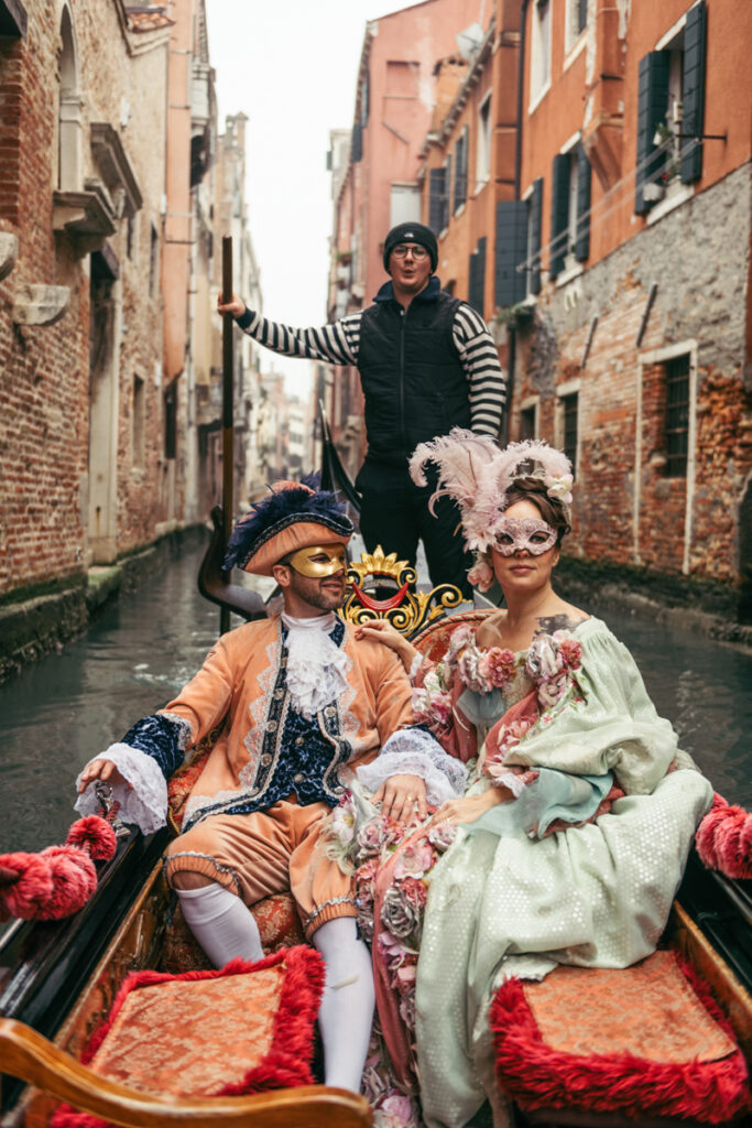 enice Carnival photoshoot of a couple dressed in historical costumes, floating through hidden canals