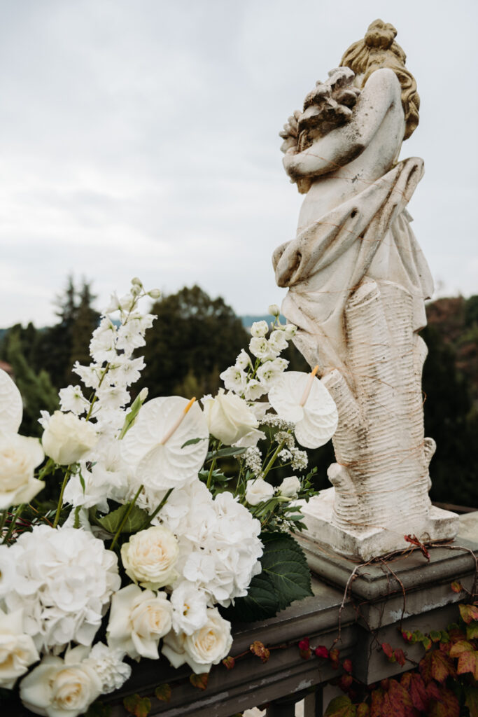 White floral arrangement with classical statue details, blending natural beauty and historic charm.