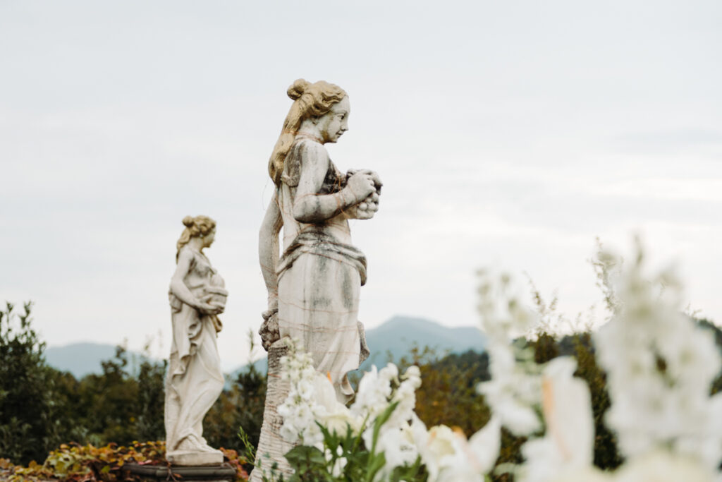 Classical statues overlooking the Italian countryside, adding timeless elegance to the outdoor elopement setting.