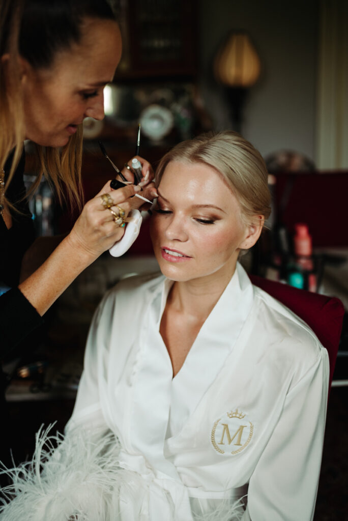 Bride having her makeup done, with soft lighting highlighting her serene expression during the getting ready moments.